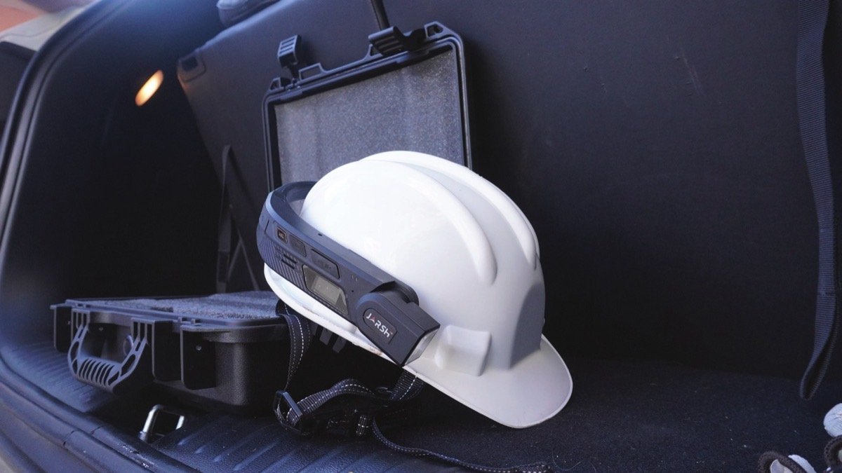 WorkAlive unit fitted to an industrial helmet beside its rugged carry case