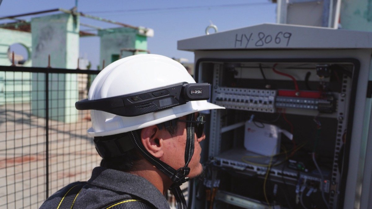 Worker wearing WorkAlive on a helmet while working hands-free inside an electrical panel