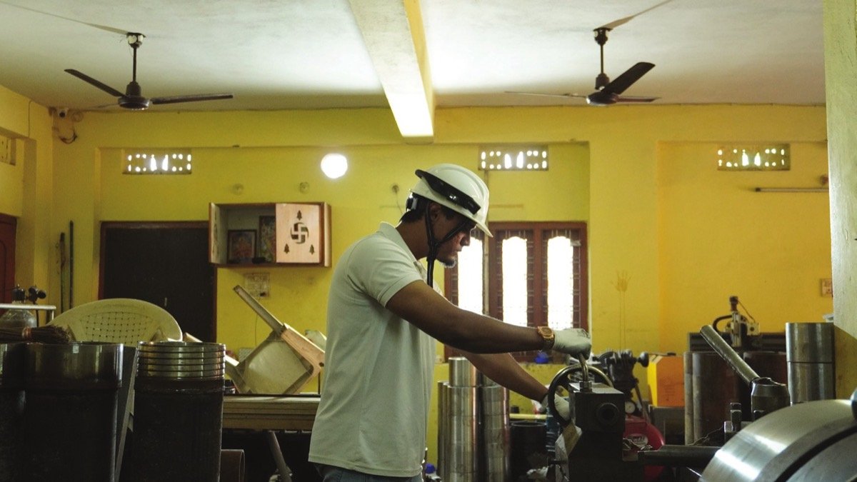 Technician wearing a WorkAlive-equipped helmet while operating workshop machinery